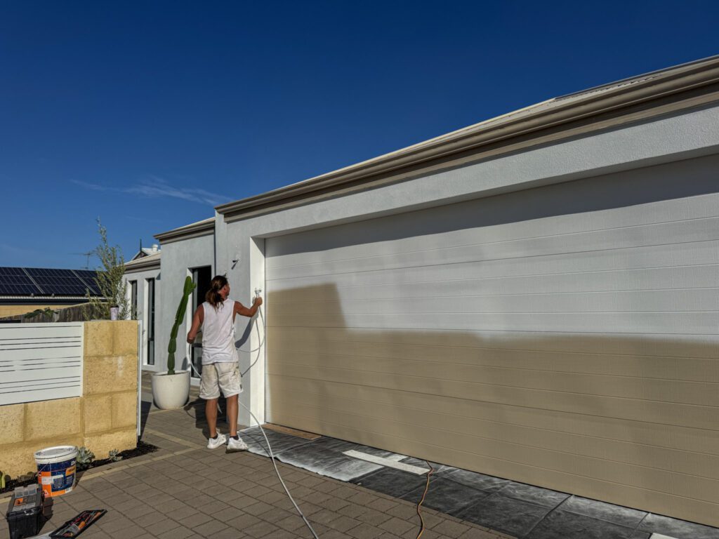Halfway through painting a dated garage door to a fresh white.